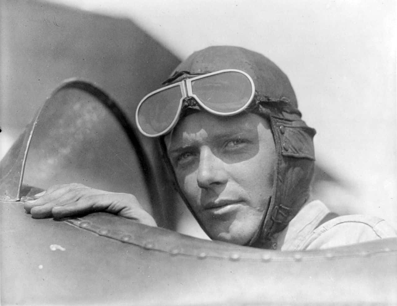 Charles Lindbergh, wearing helmet with goggles up, in open cockpit of airplane