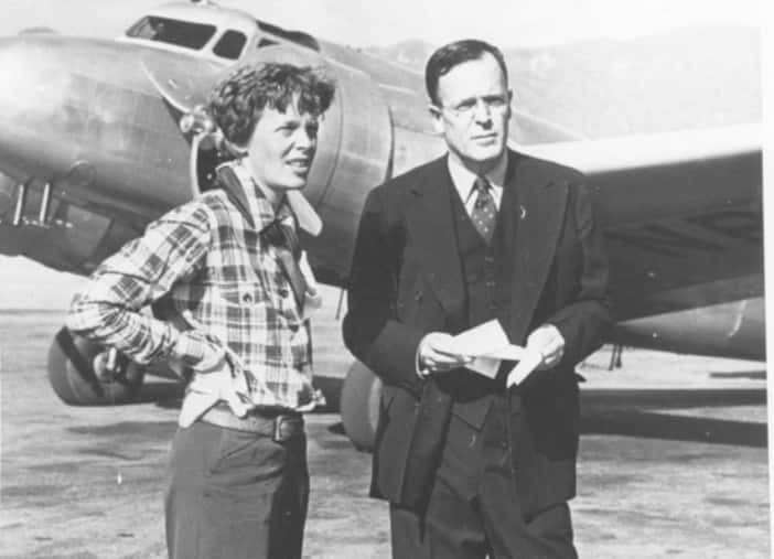 Amelia Earhart standing in front of an aircraft