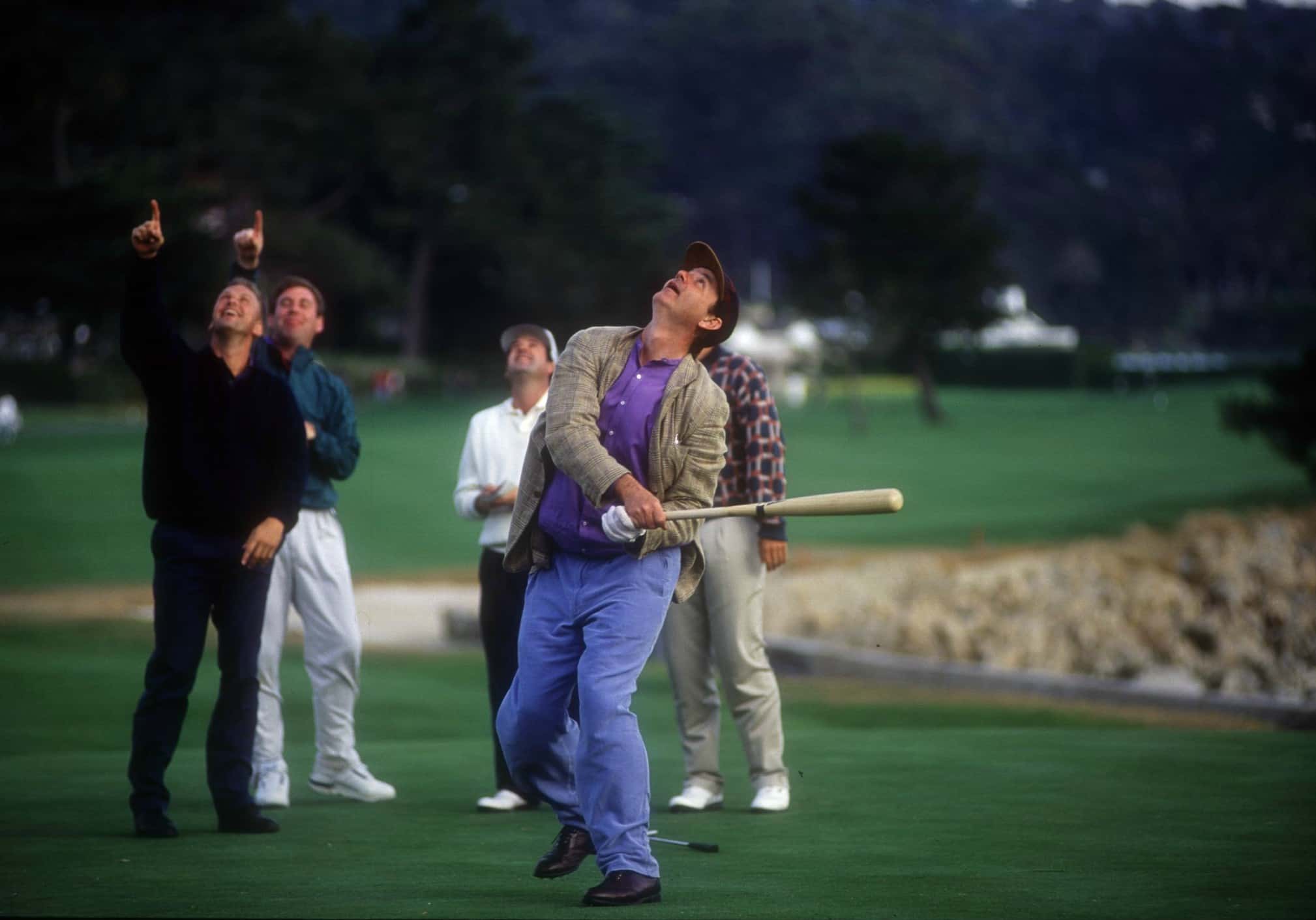 COMEDIAN BILL MURRAY BATS HIS GOLF BALL WITH A BASEBALL BAT