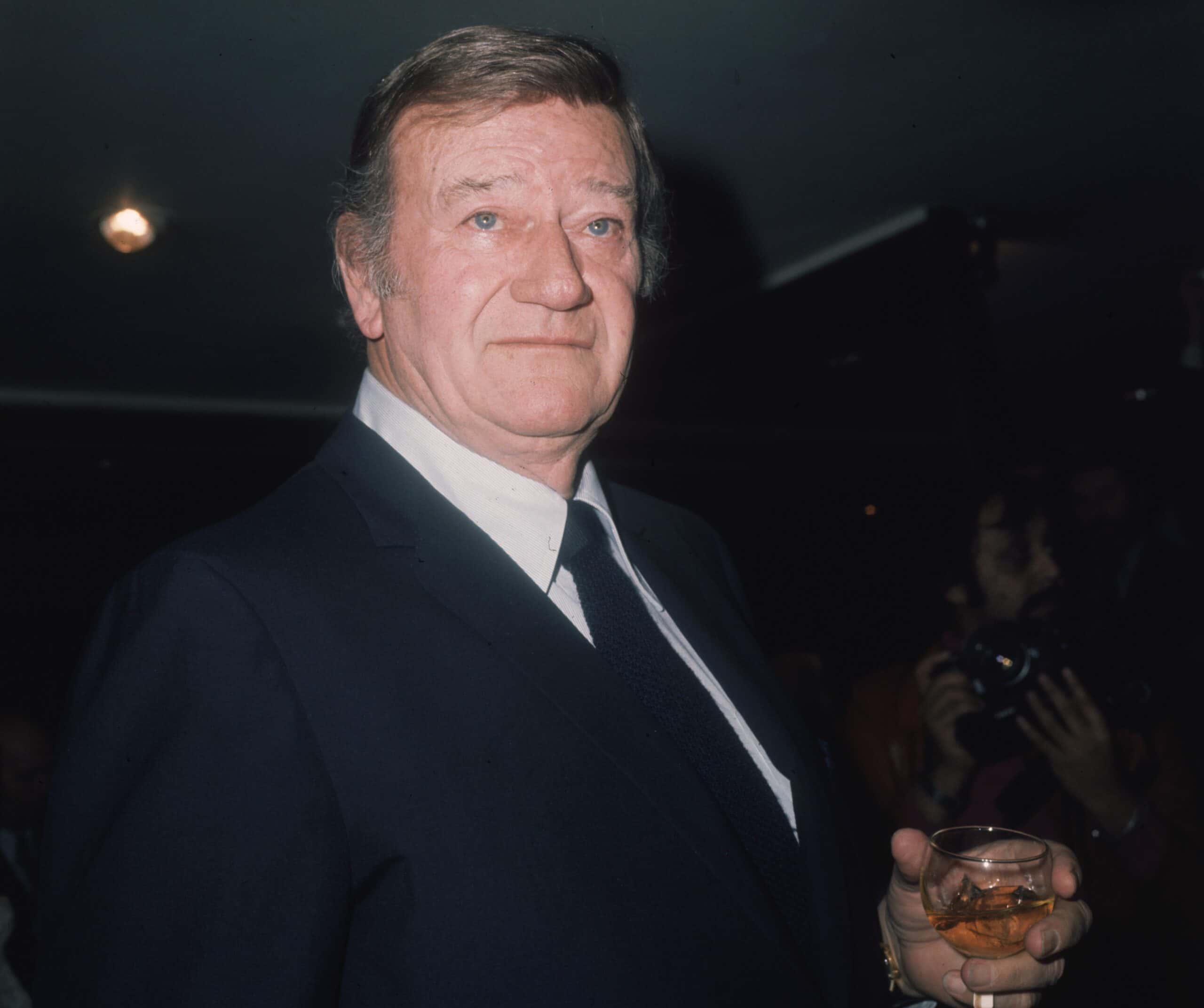 American film star John Wayne (1907 - 1979) promoting his latest film 'McQ'. Wearing a dark blue suit, facing the camera