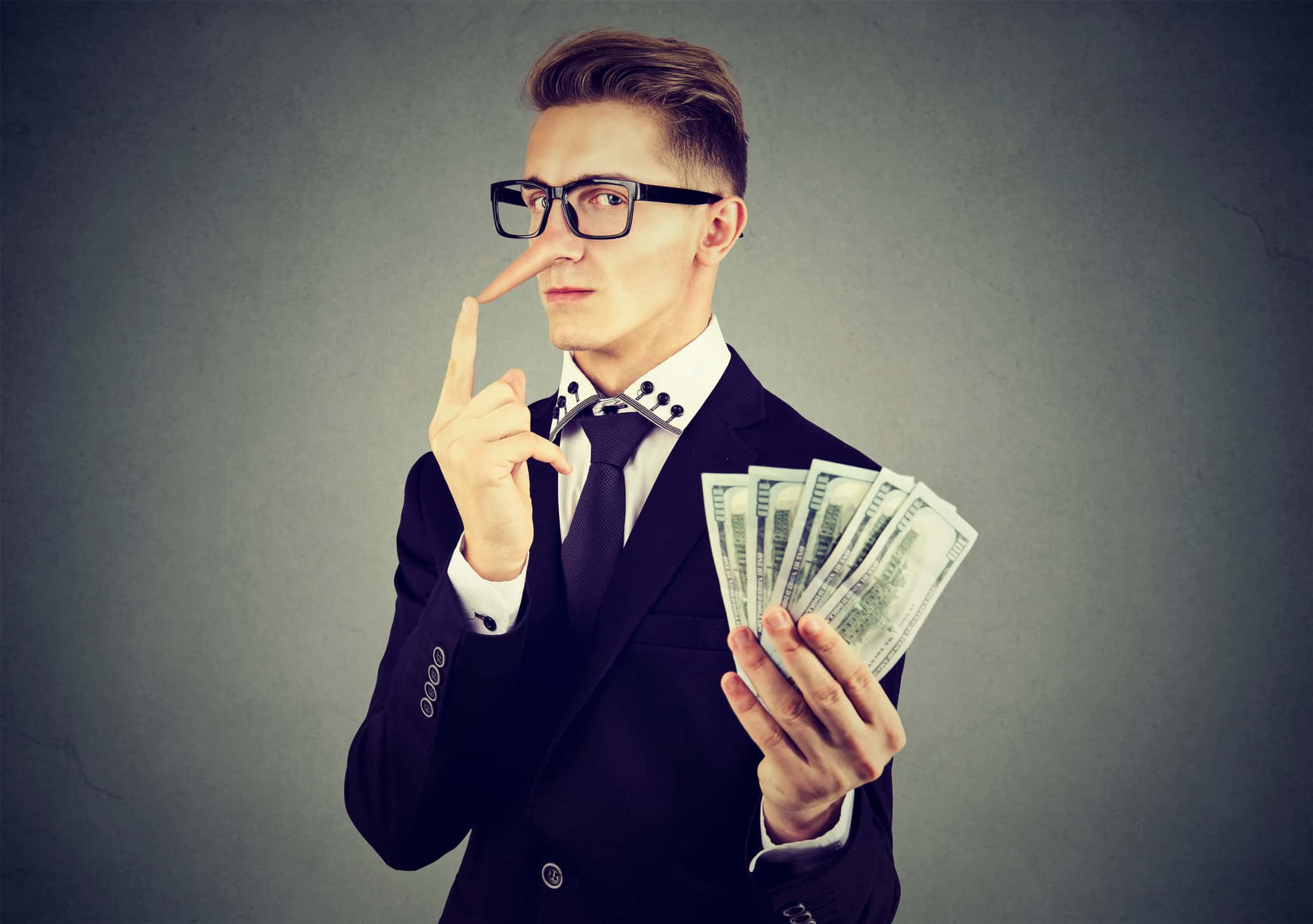 Liar young business man in suit and glasses with dollar cash