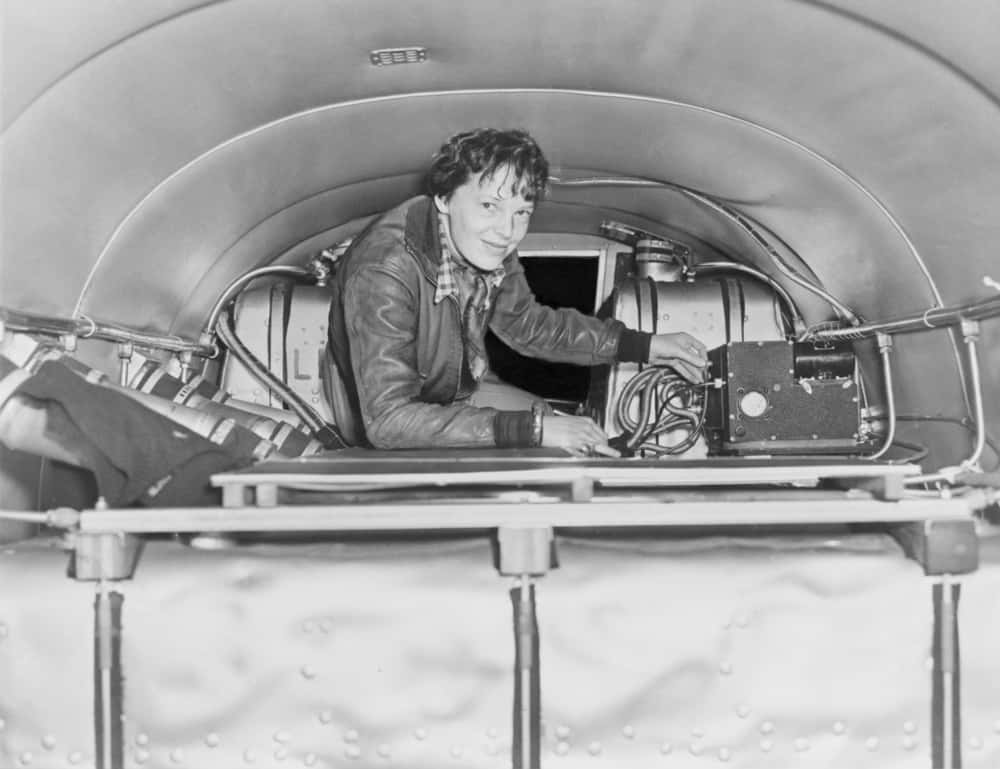 Amelia Earhart (1897-1937), checking equipment on her airplane