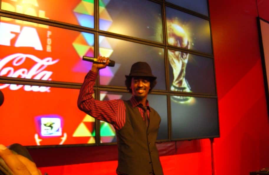 Portrait Photo of K'naan in brown outfit and hat