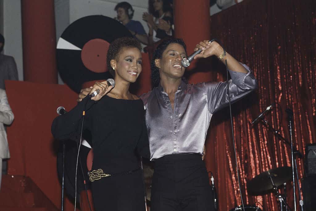 Whitney Houston in black dress is performing with Jermaine Jackson on stage - 1984