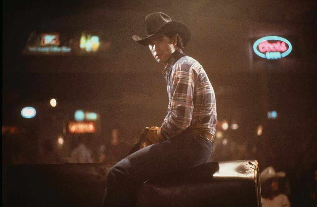 Actor John Travolta rides a mechanical bull in a scene during the Paramount Pictures movie 'Urban Cowboy