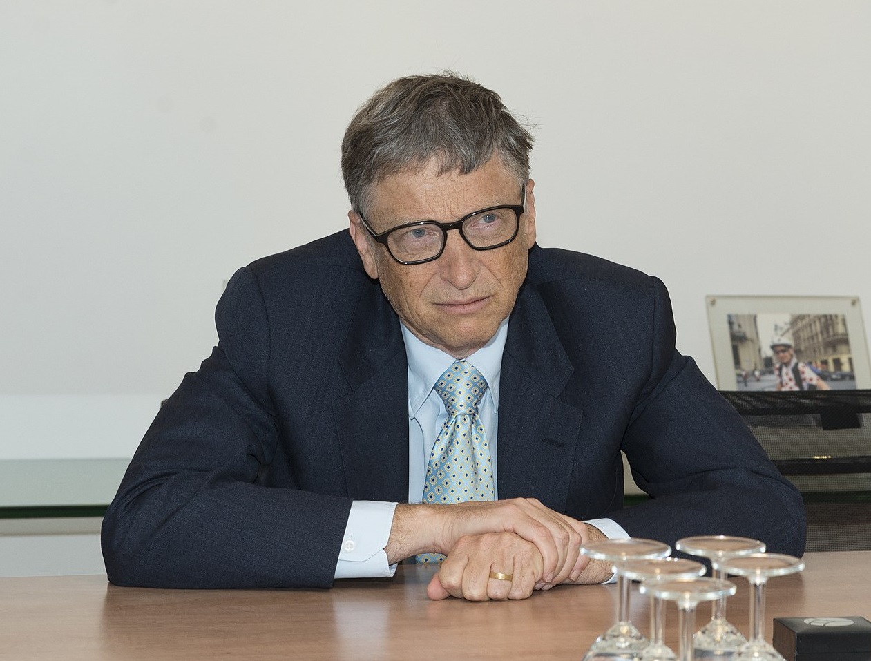 Portrait Photo of Bill Gates in a dark suit, looking to another person