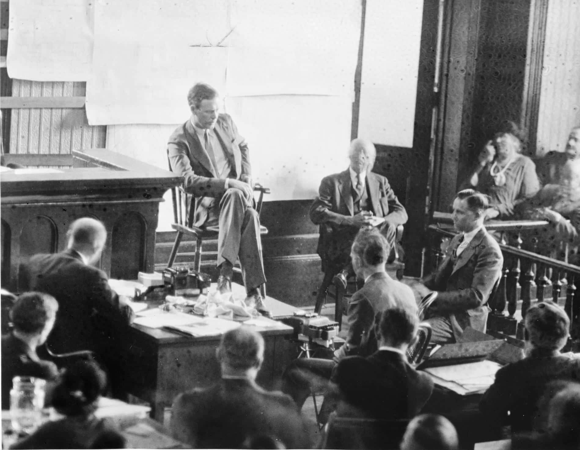 Lindbergh testifying at Hauptmann's trial. Hauptmann is in half-profile at right.