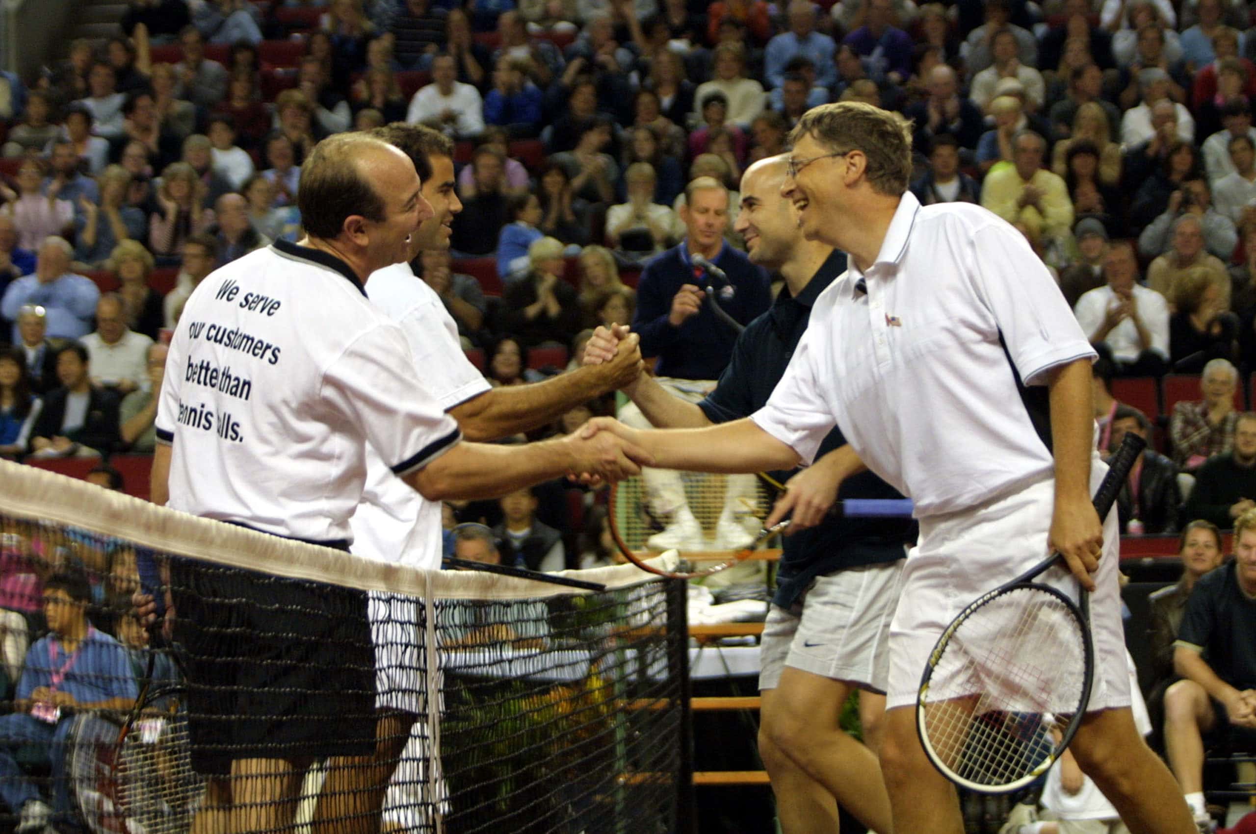 Tennis players Andre Agassi (2nd L) and Pete Sampras shake hands at the net as Microsoft founder Bill Gates (R) and Amazon.com founder Jeff Bezos
