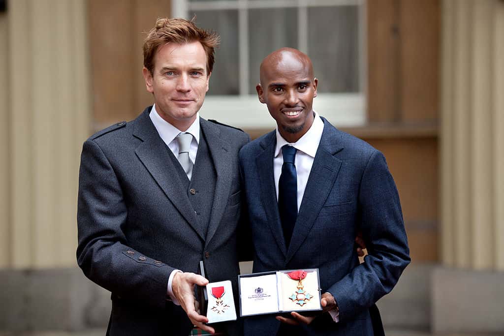 Ewan McGregor holds his OBE with Double Olympic Gold Medal winning athlete Mo Farrah as he holds his CBE