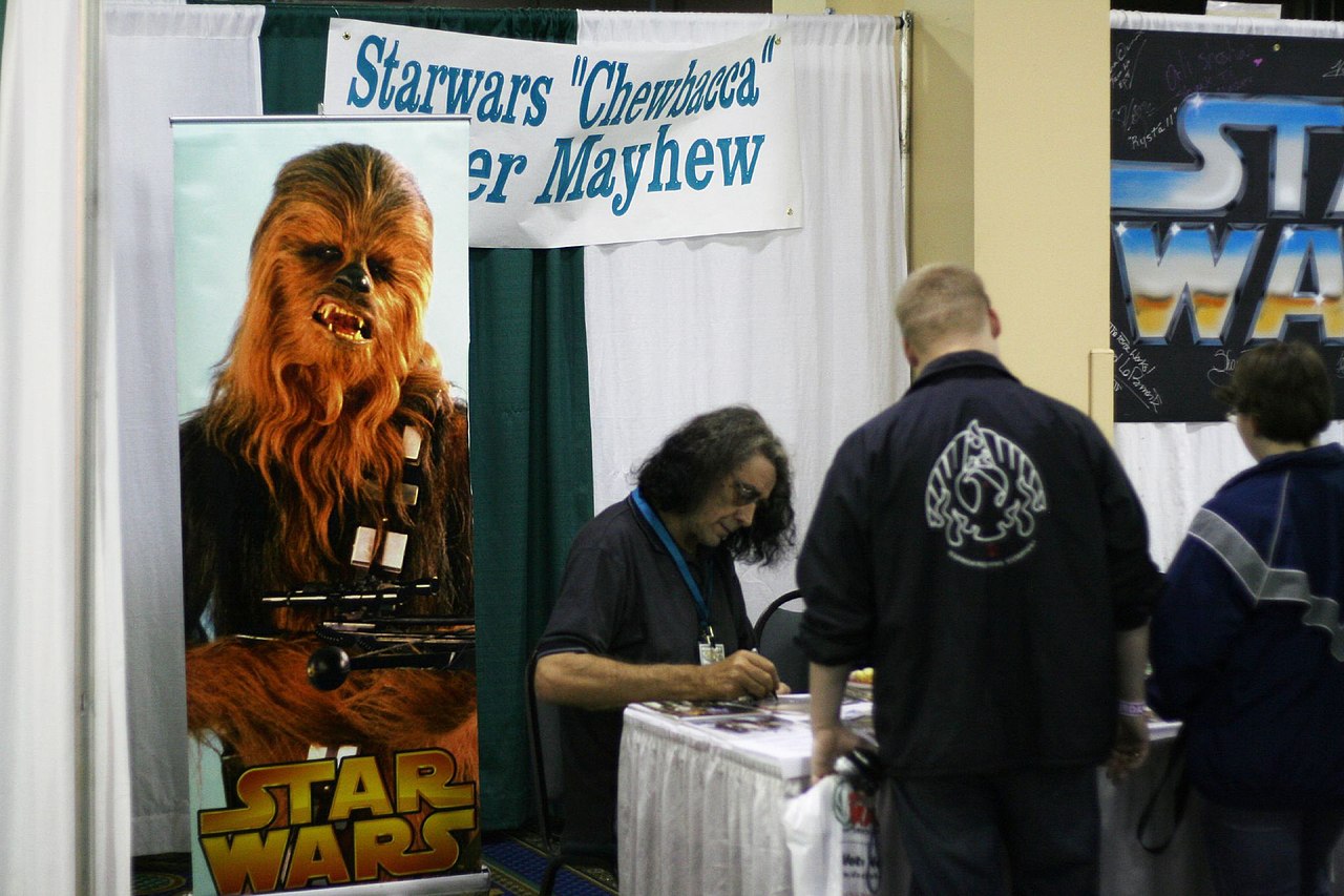  Peter Mayhew, who played Chewbacca sitting on a table 