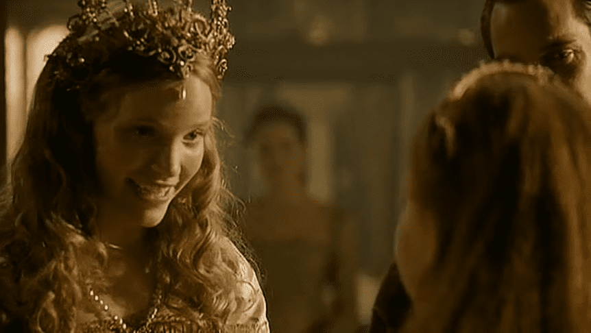 Screenshot of Catherine Howard with long hair wearing pearl earrings is talking and looking happy - from The Tudors (2007–2010)