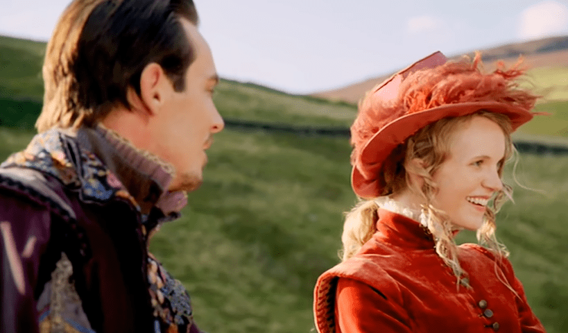 Screenshot of Catherine Howard with long hair wearing red dress and red hat is smiling - from The Tudors (2007–2010)