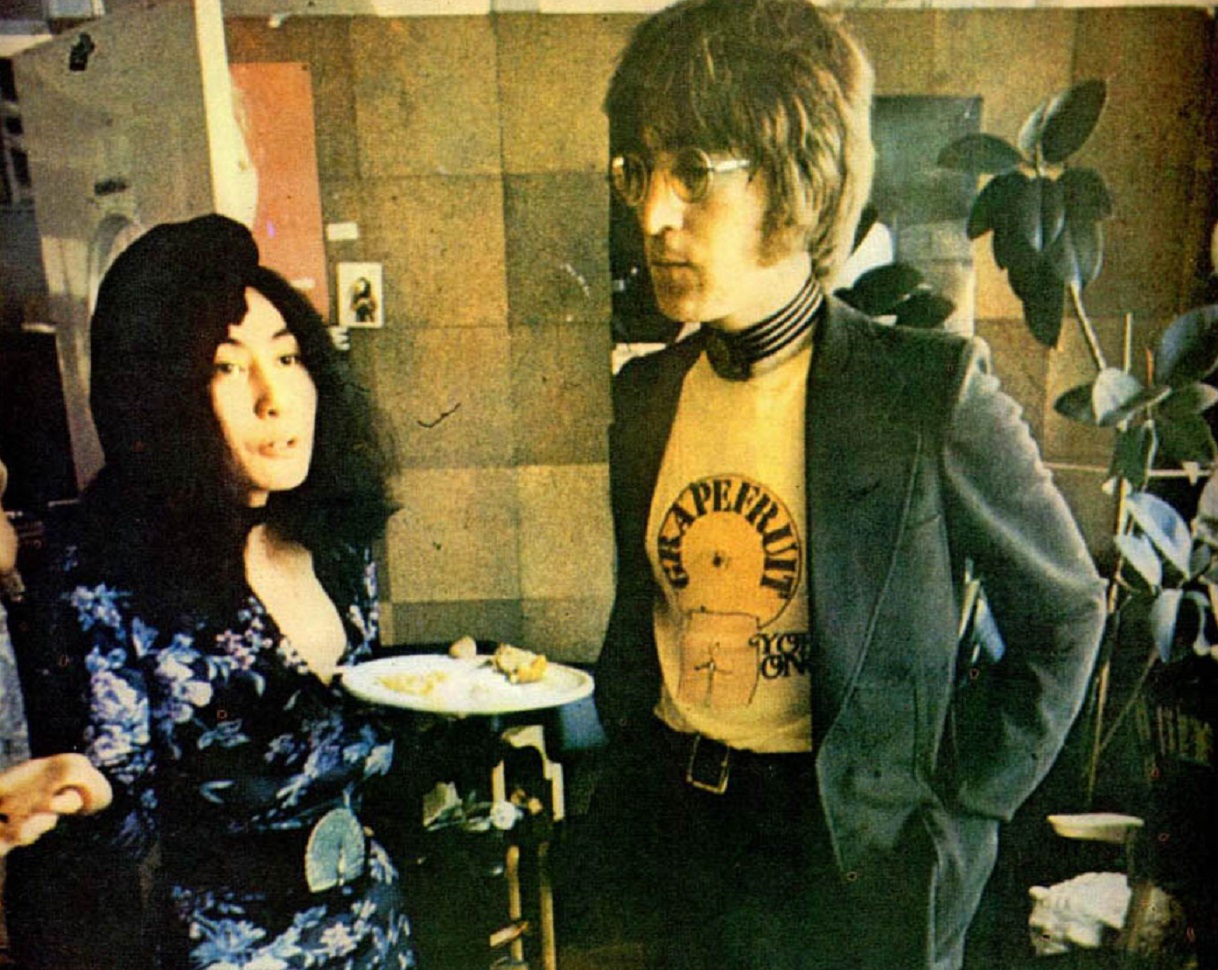 Portrait Photo of Yoko Ono and John Lennon standing next to a dining table