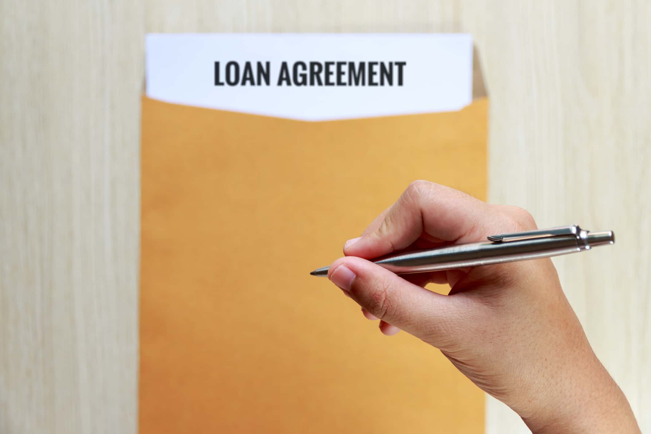 Hand Holding Pen Over Loan Agreement