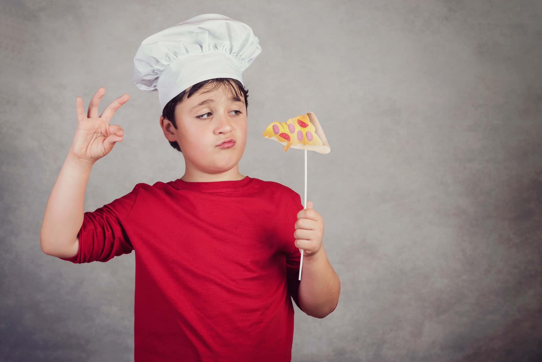 Boy Holding Artificial Pizza While Standing Against Wall.