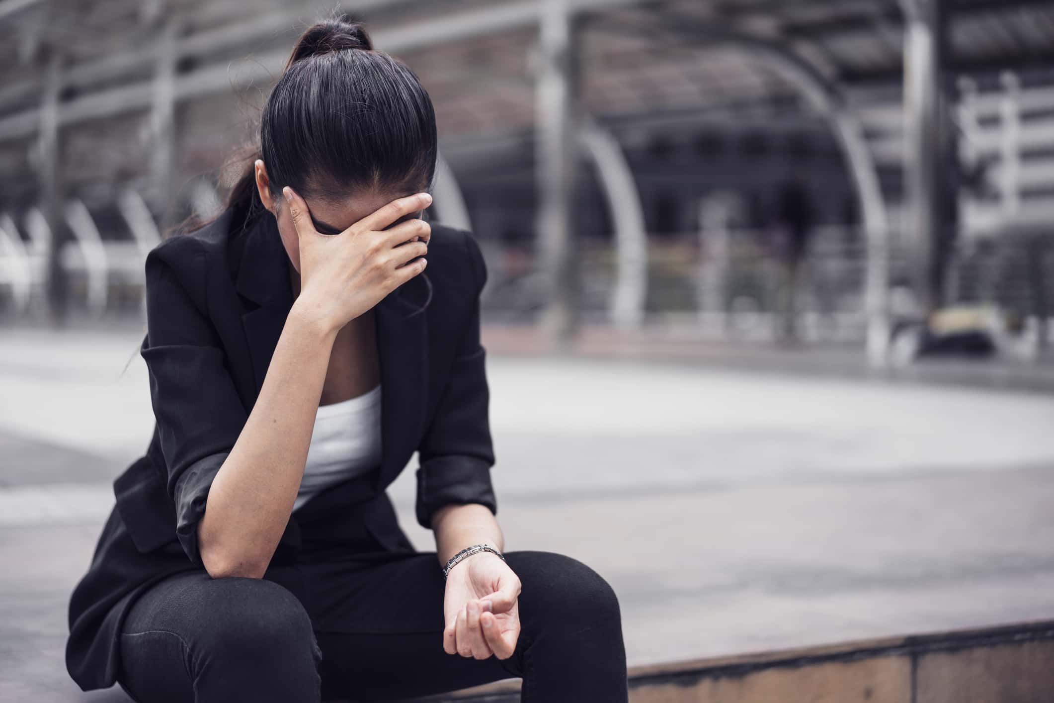 Tensed Businesswoman Sitting On Street In City.