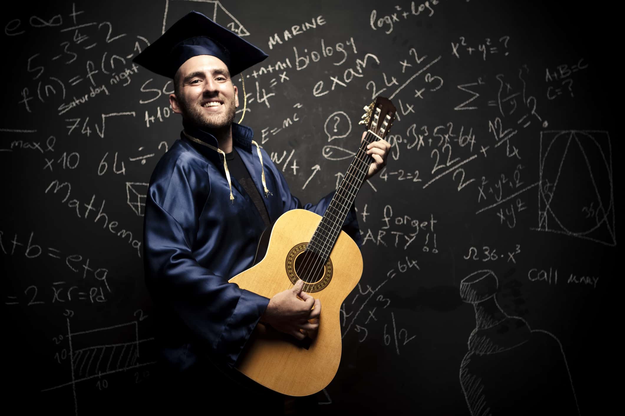 New graduate posing in front of a blackboard.