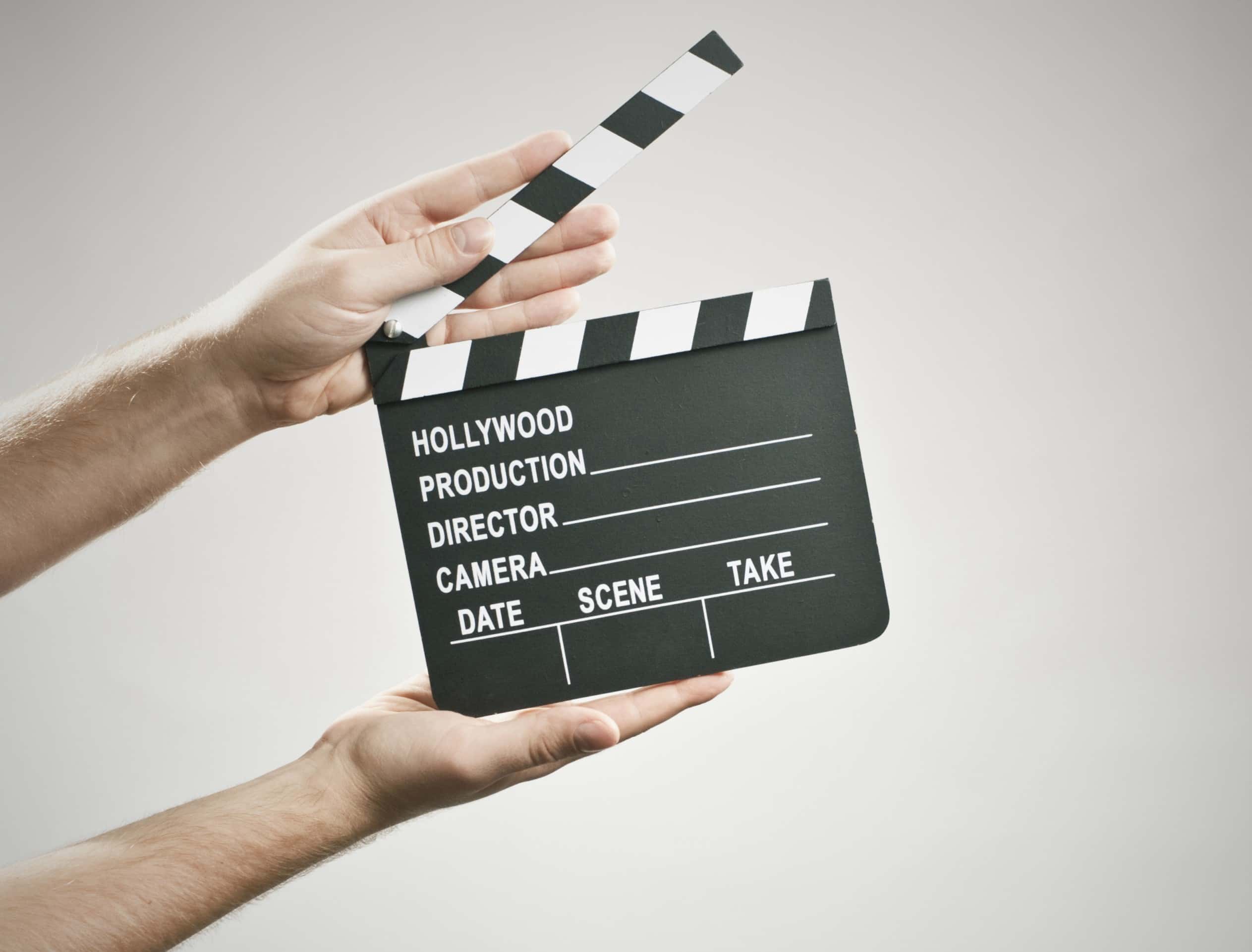 Two hands holding a clapperboard on a white background.