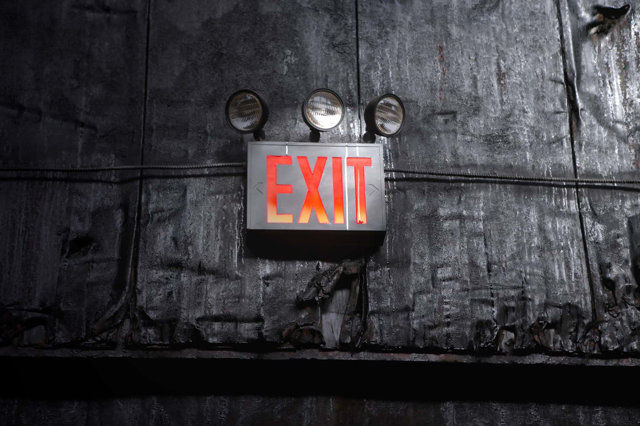Exit sign on a black dilapidated wall.