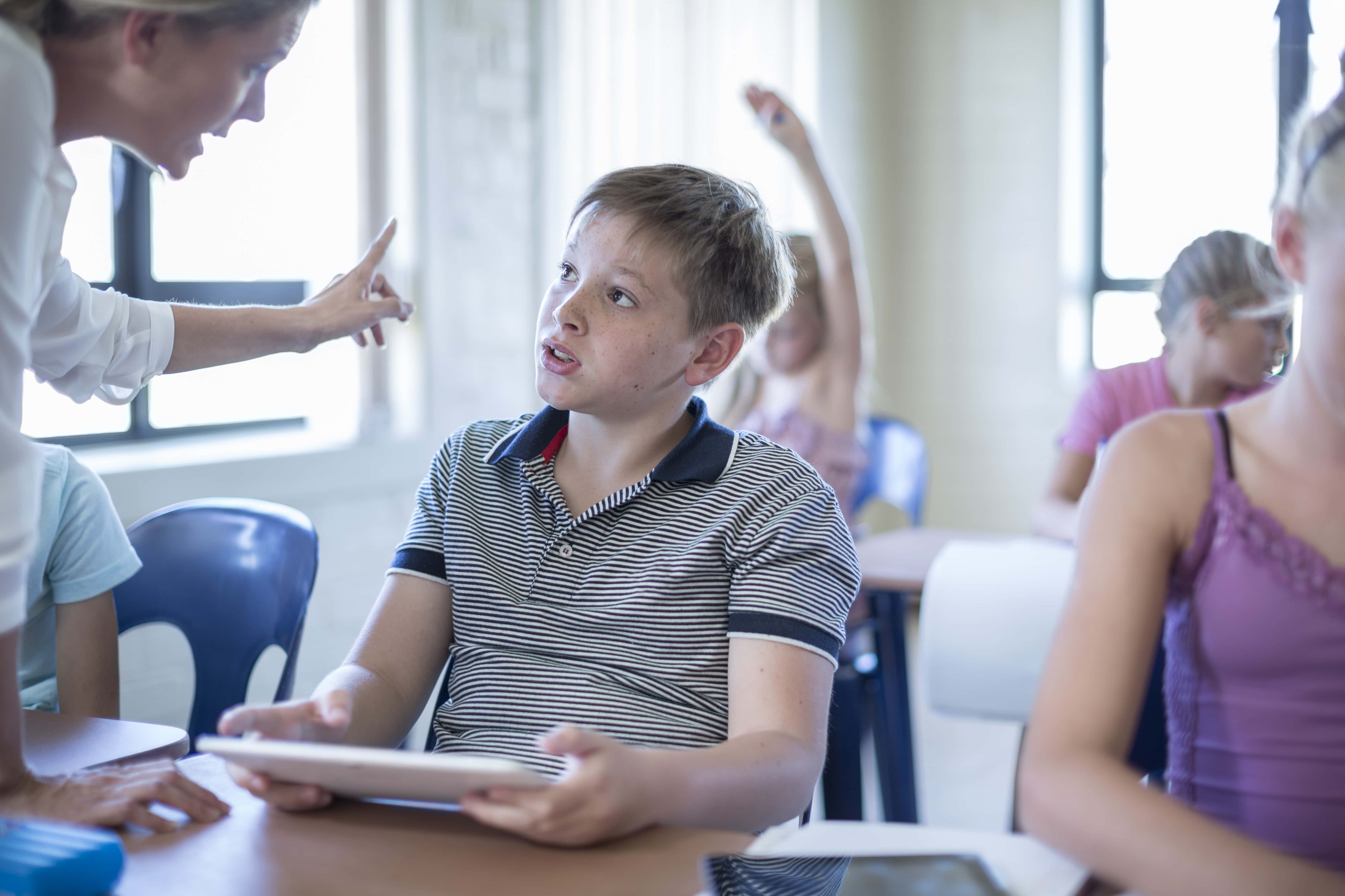 Teacher in classroom scolding schoolboy.