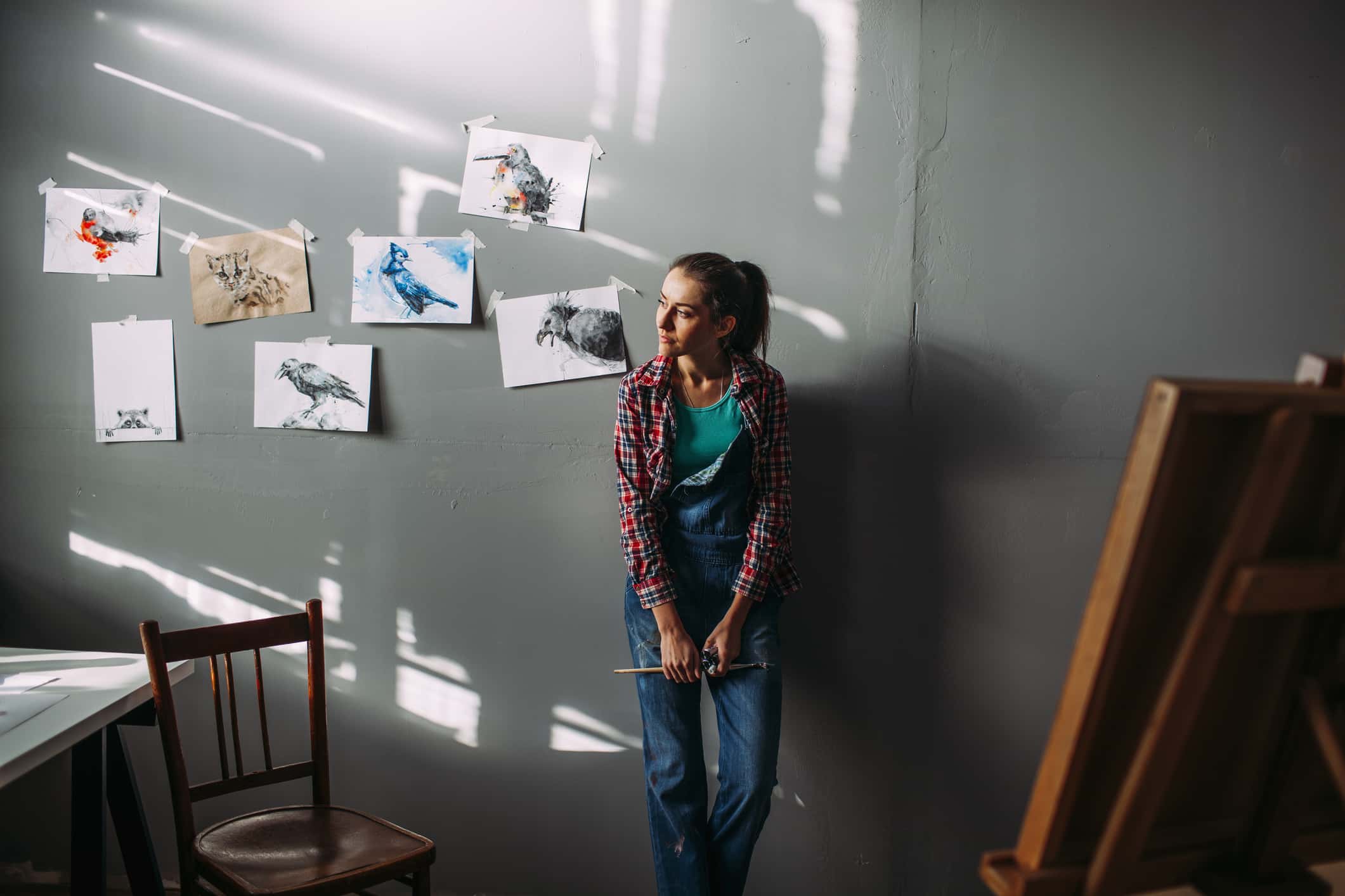 Thoughtful painter leaning on wall in art studio