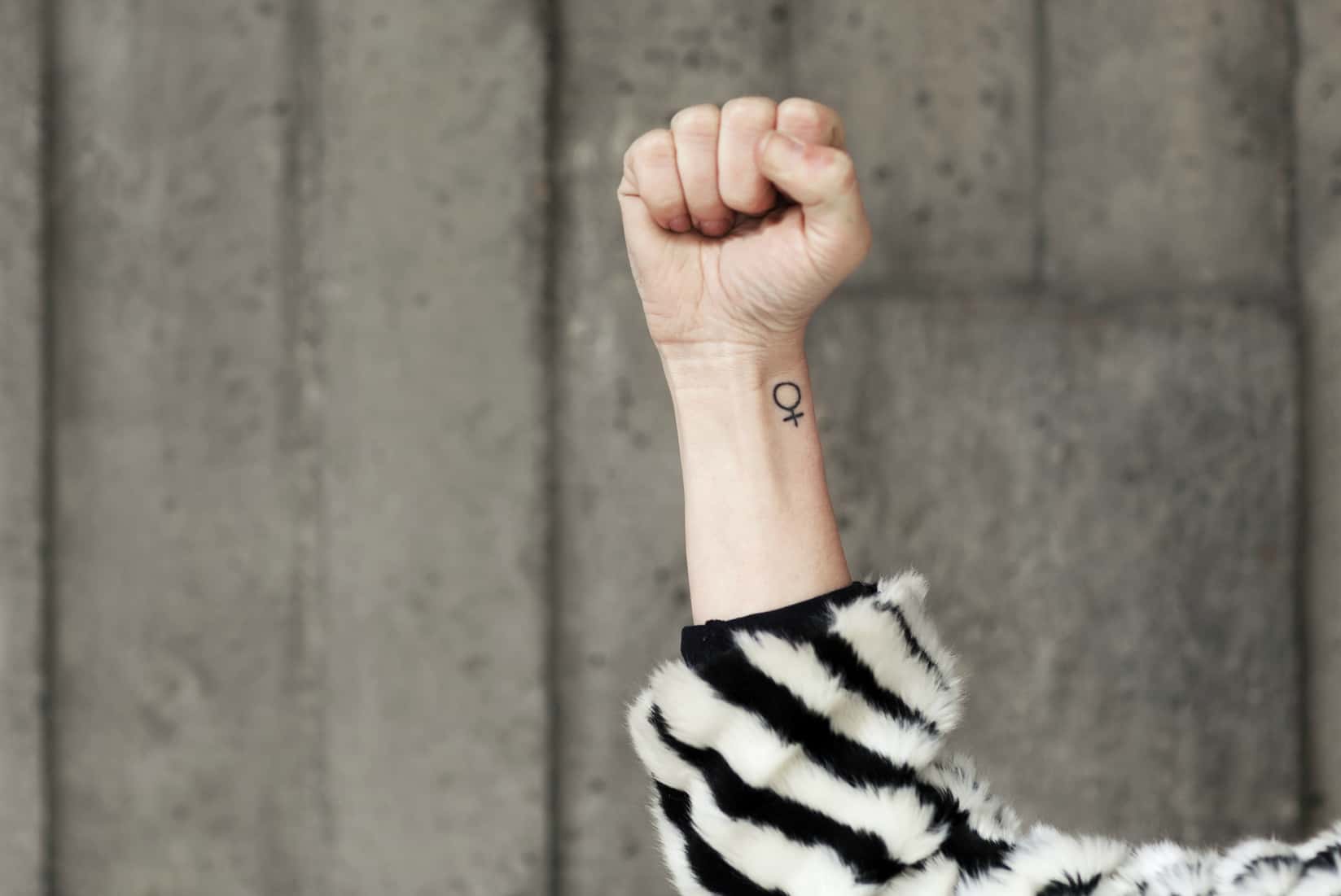Clenched fist and female symbol on arm.