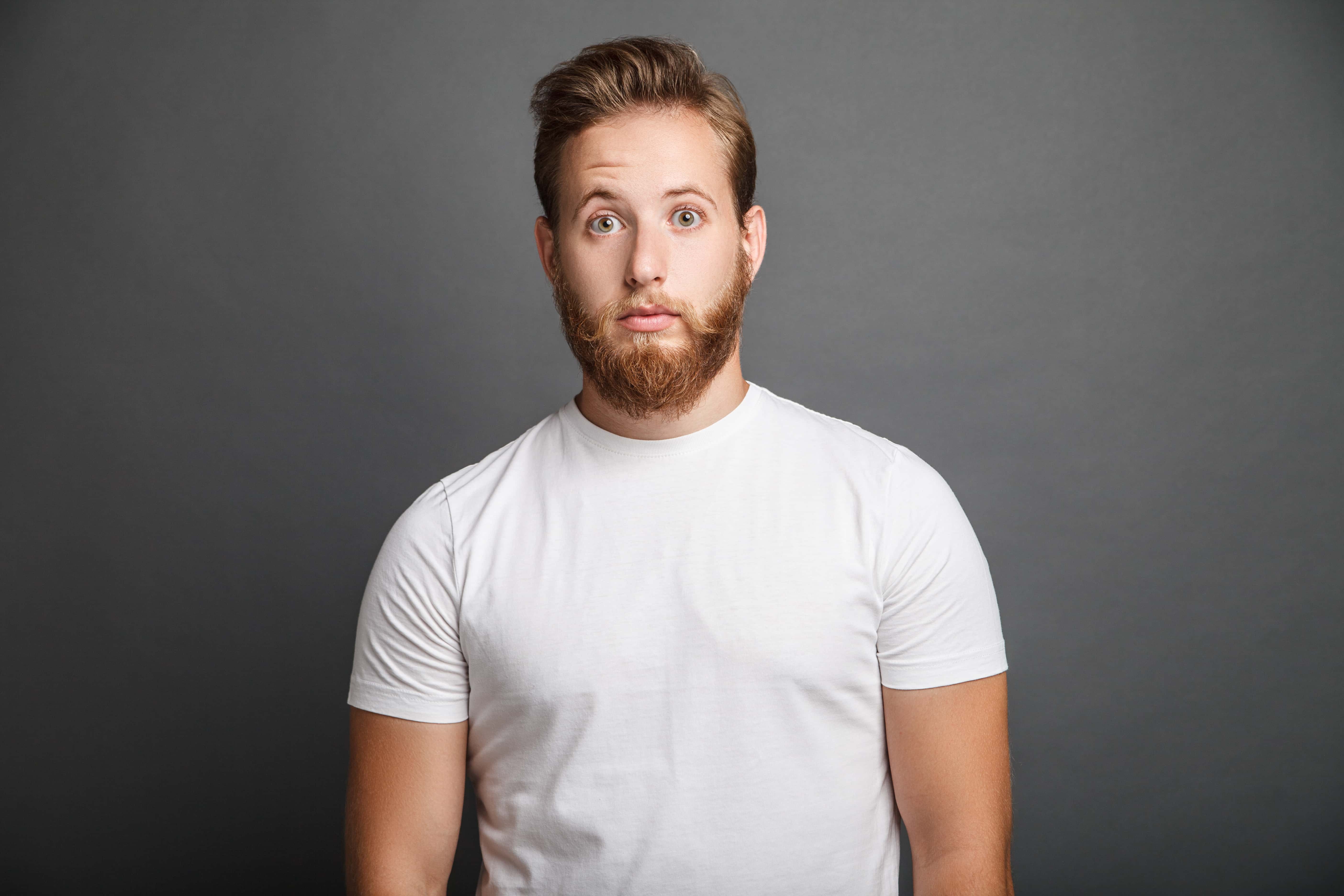 Surprised young man posing on gray background.