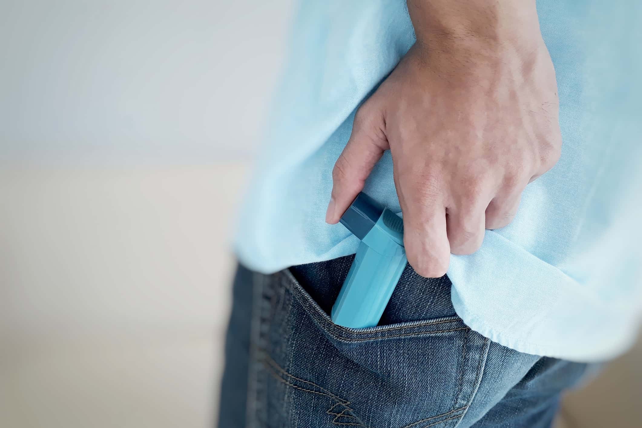 Midsection Of Man Removing Asthma Inhaler From Pocket At Home.