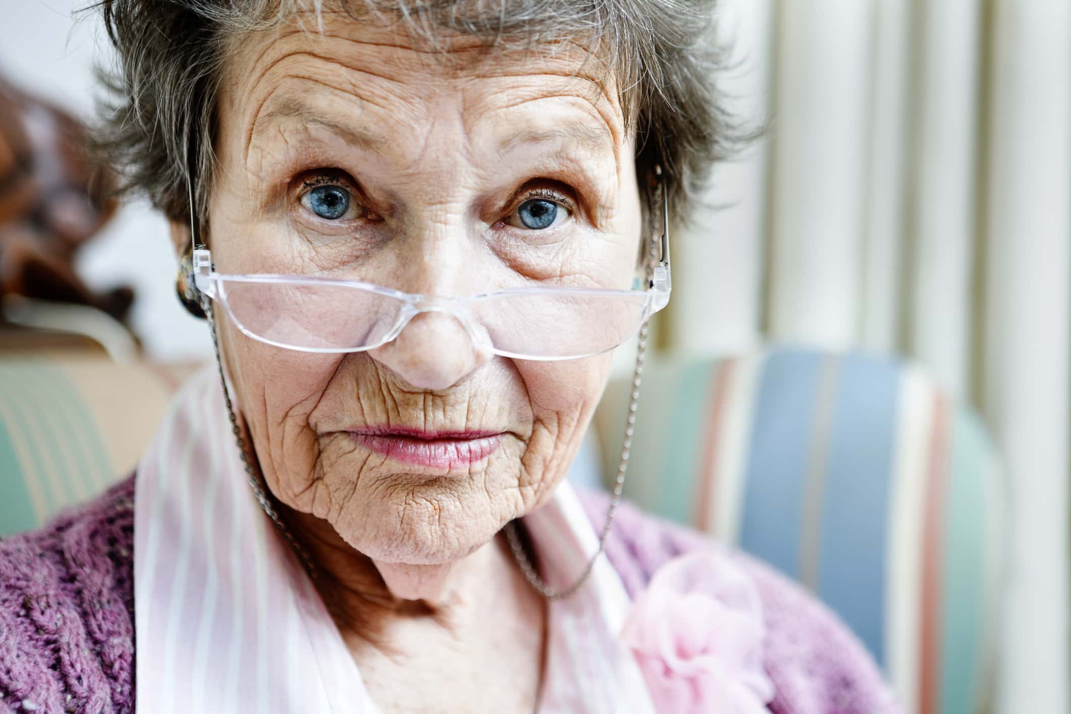 Old lady looks over spectacles with eyebrows raised.