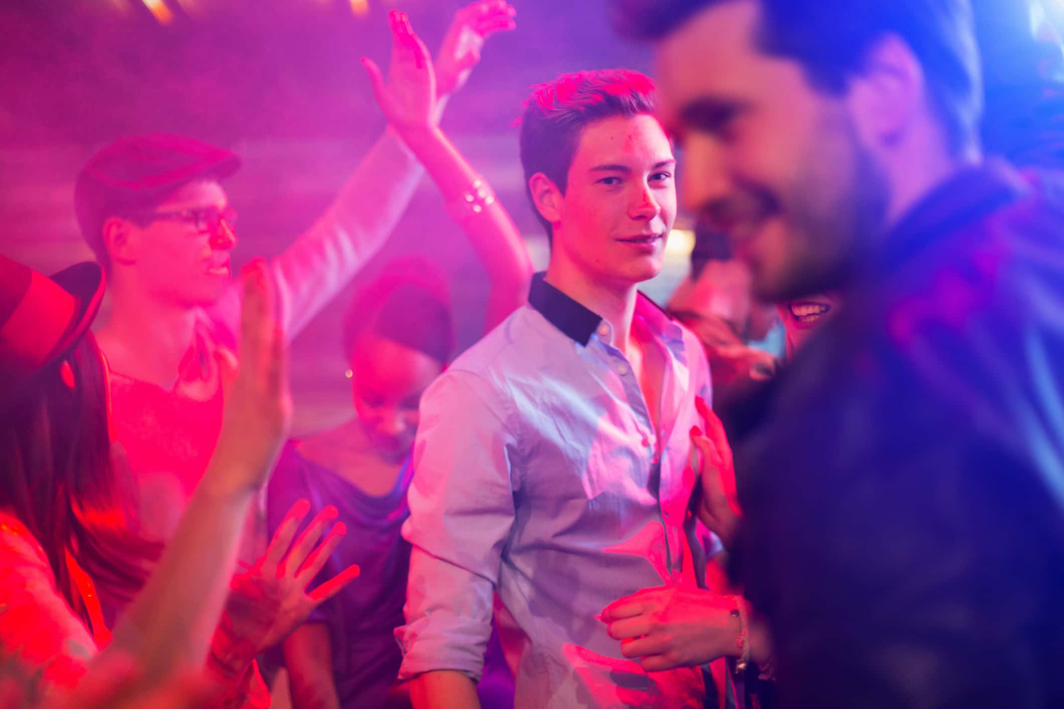 Teenage boy surrounded by group of people dancing at party.
