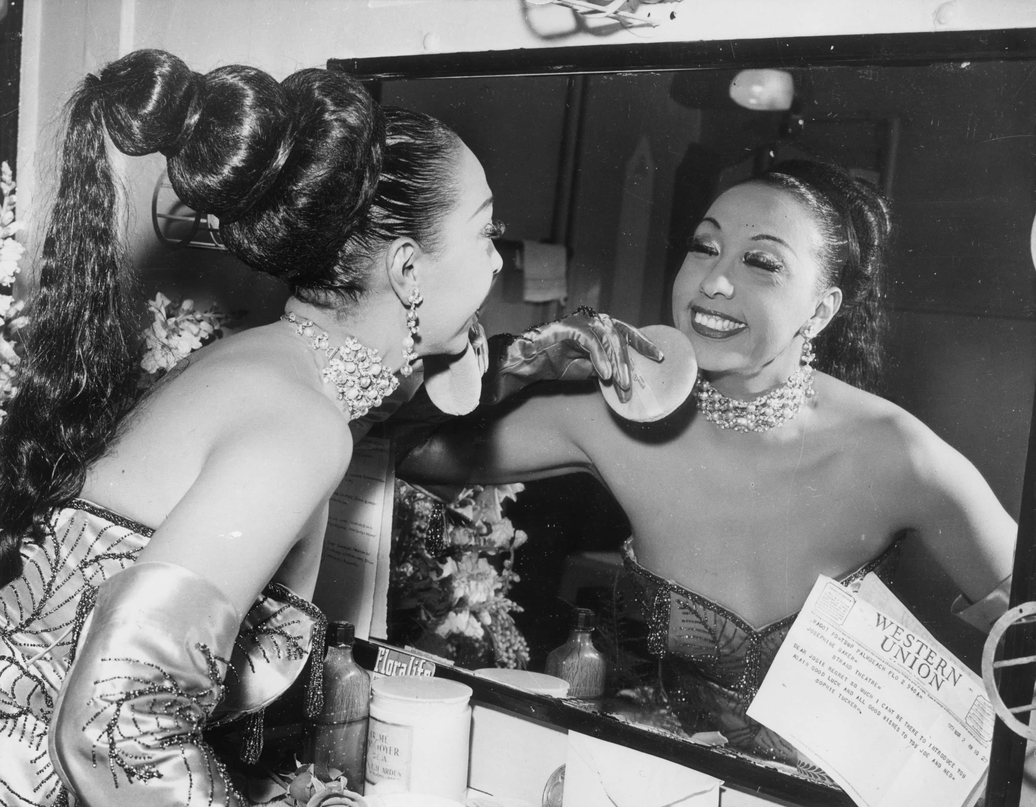  American-born cabaret singer Josephine Baker (1906 - 1975) applies makeup with a powder puff