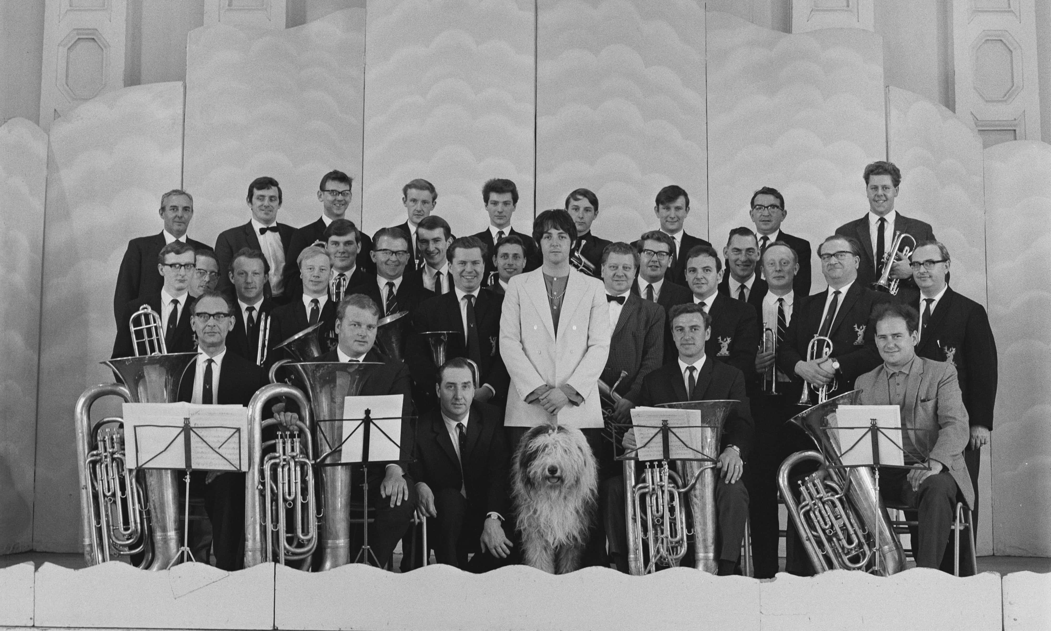 English musician, singer, songwriter, and composer Paul McCartney (centre) with his dog 'Martha' and the Black Dyke Mills Band