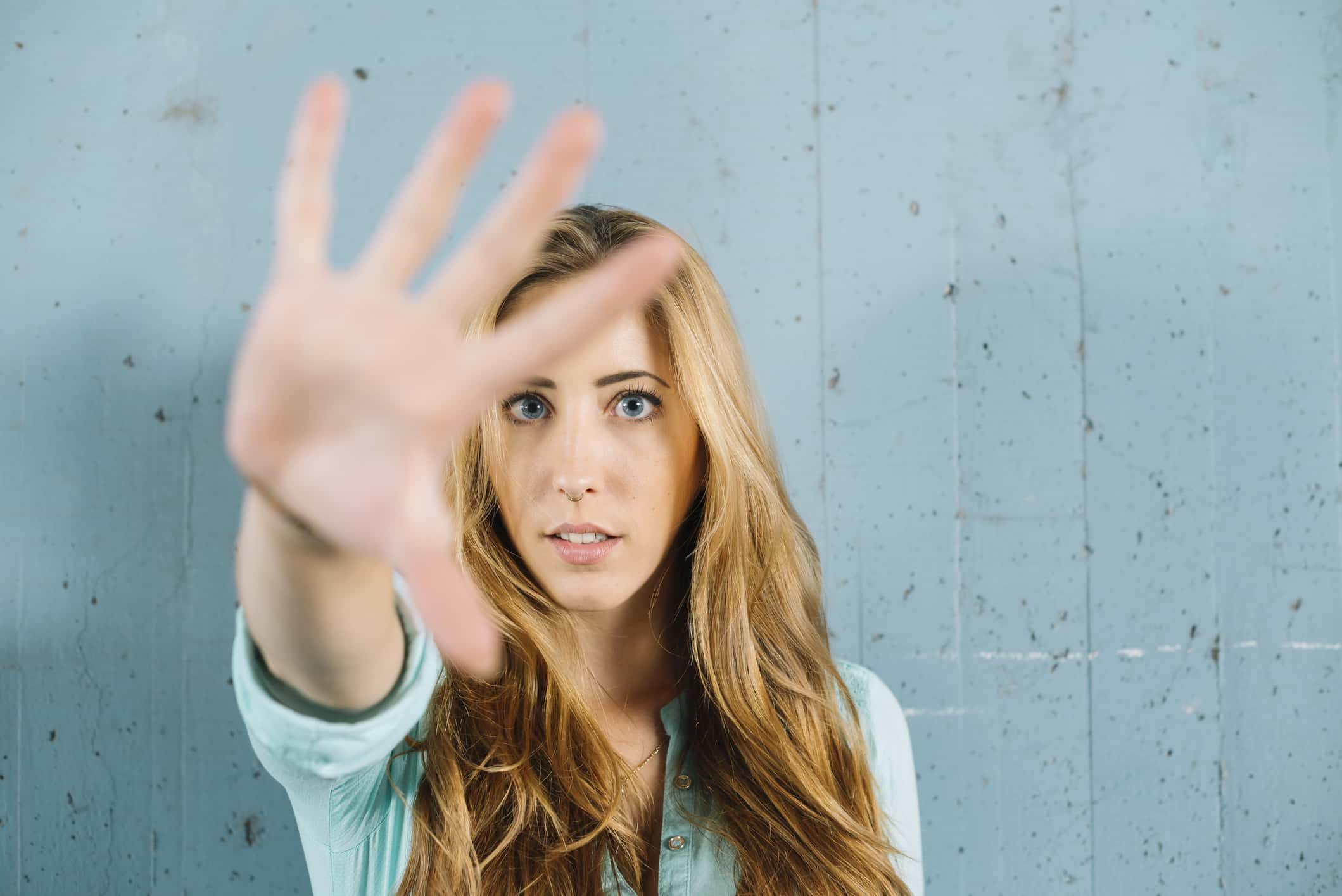 Young blond woman raising her hand.