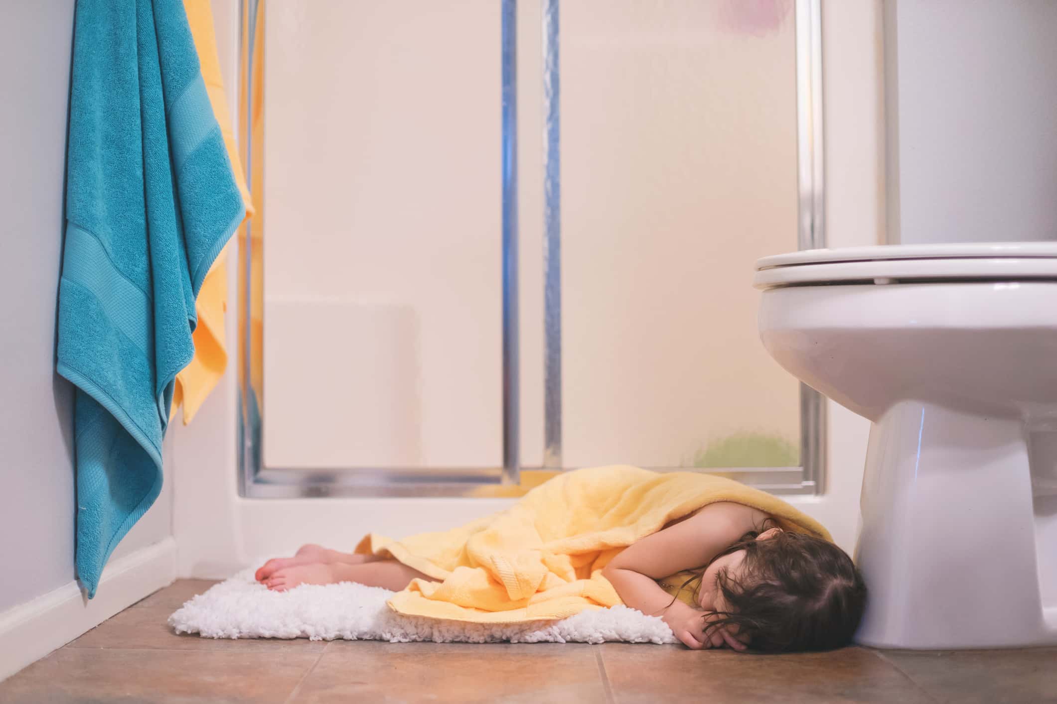 Girl sleeping on bathroom mat.