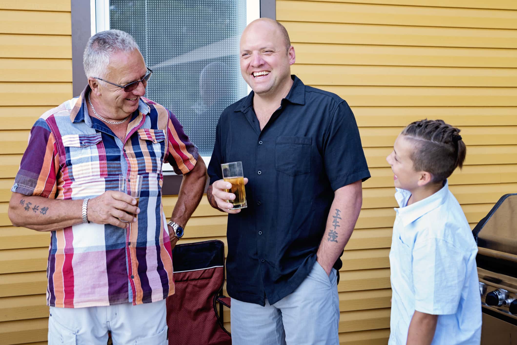Three generations of men relaxing at family barbecue.