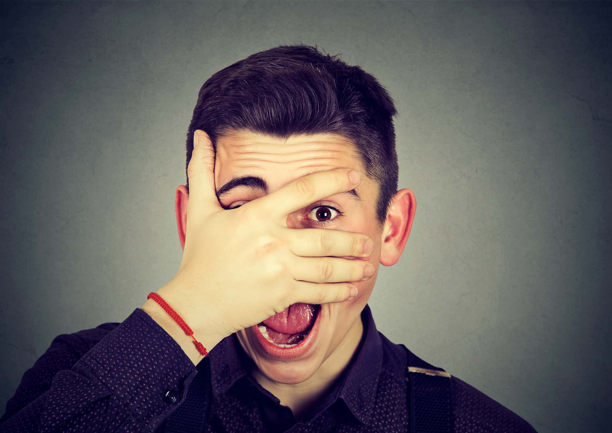 Young man looking trough his fingers.