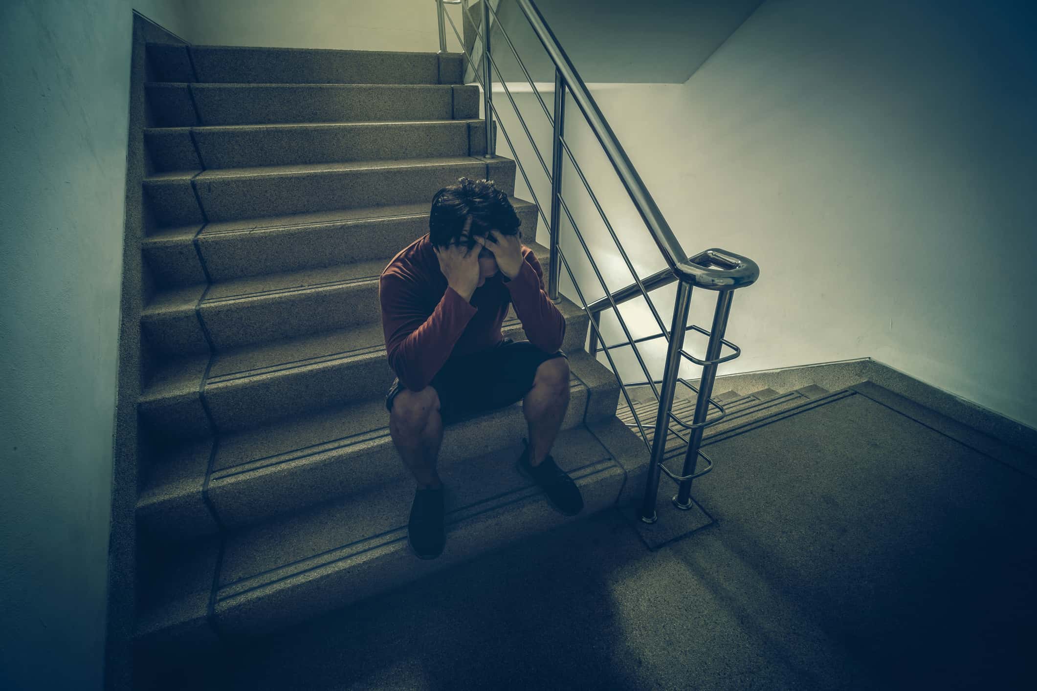 Depressed man sitting head in hands on the staircase.