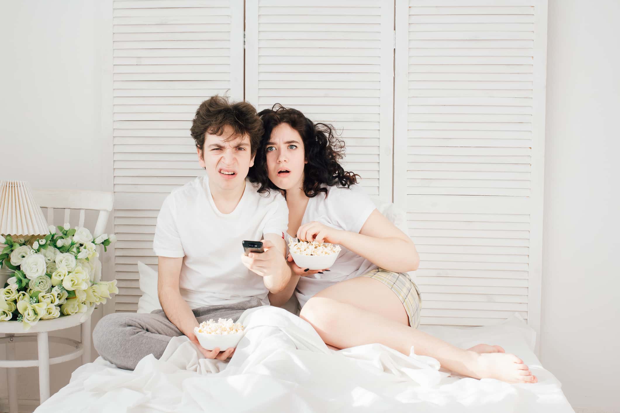Love couple watching TV in bed.