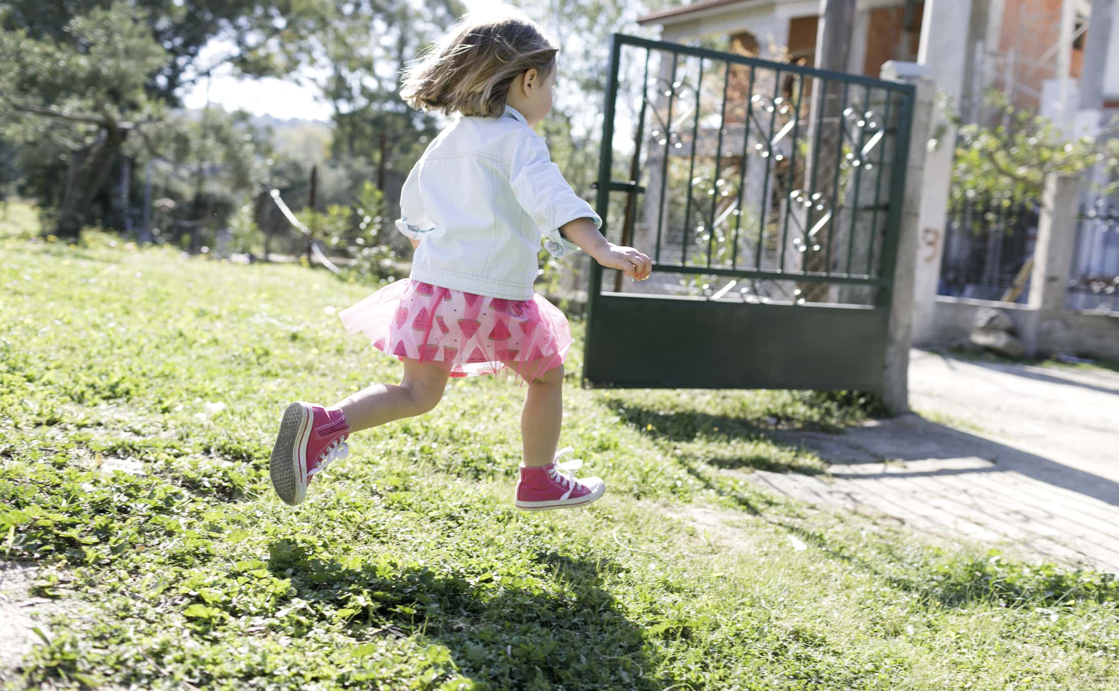 Little girl running on meadow in the garden.