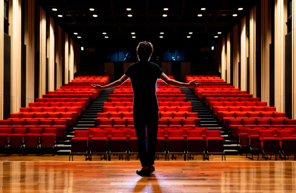 Portrait Photo of Young actor in a theater facing the seats