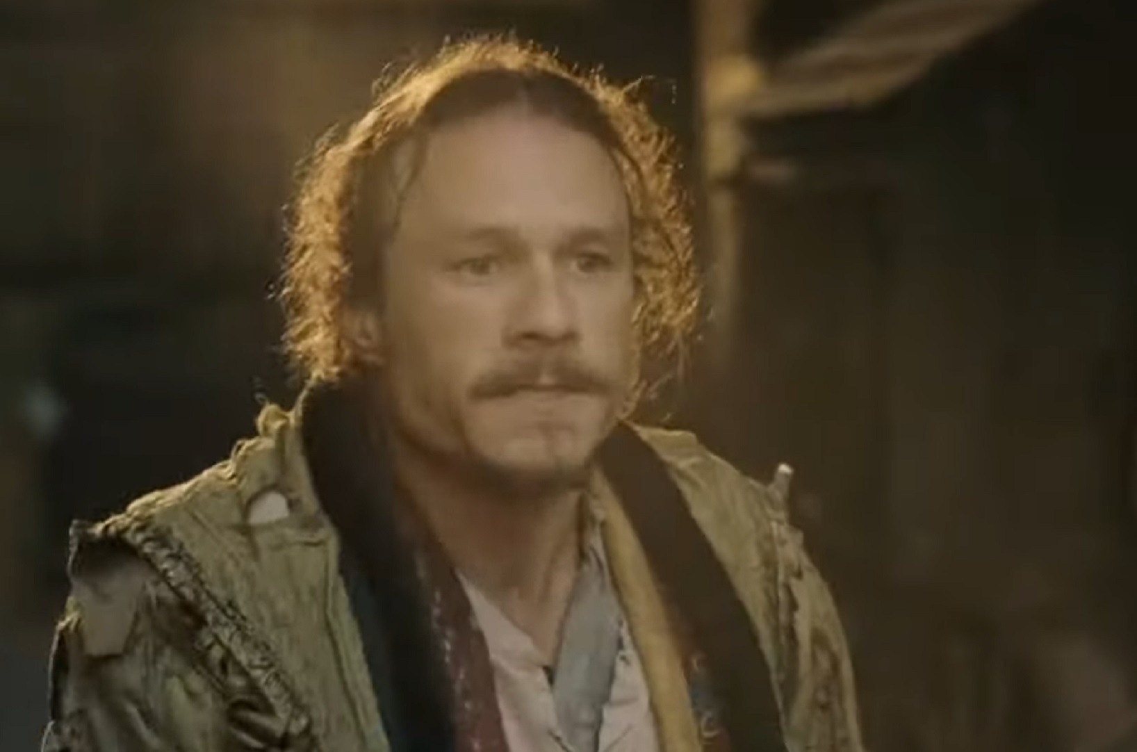 Screenshot: Heath Ledger wearing grey jacket and looking upset