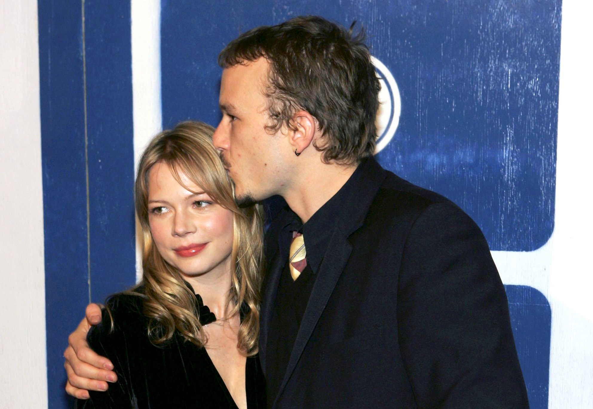 Heath Ledger and Michelle Williams wearing black suits hugging , 2005