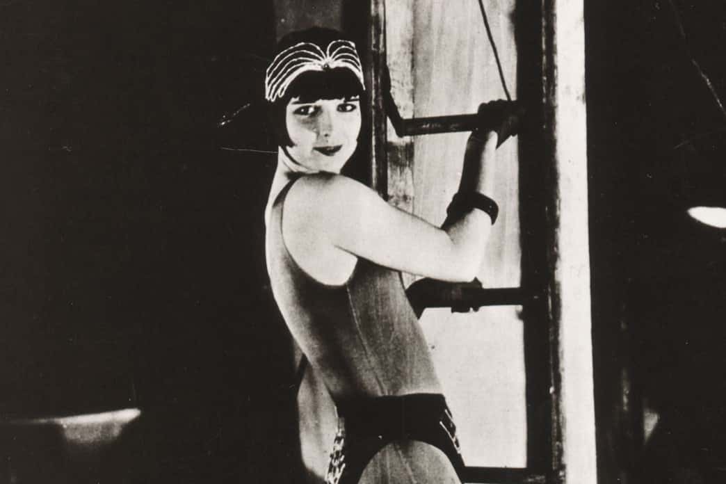 Grayscale Portrait Photo of the actress Louise Brooks from the movie A Girl in Every Port, wearing dark outfit, climbing stairs