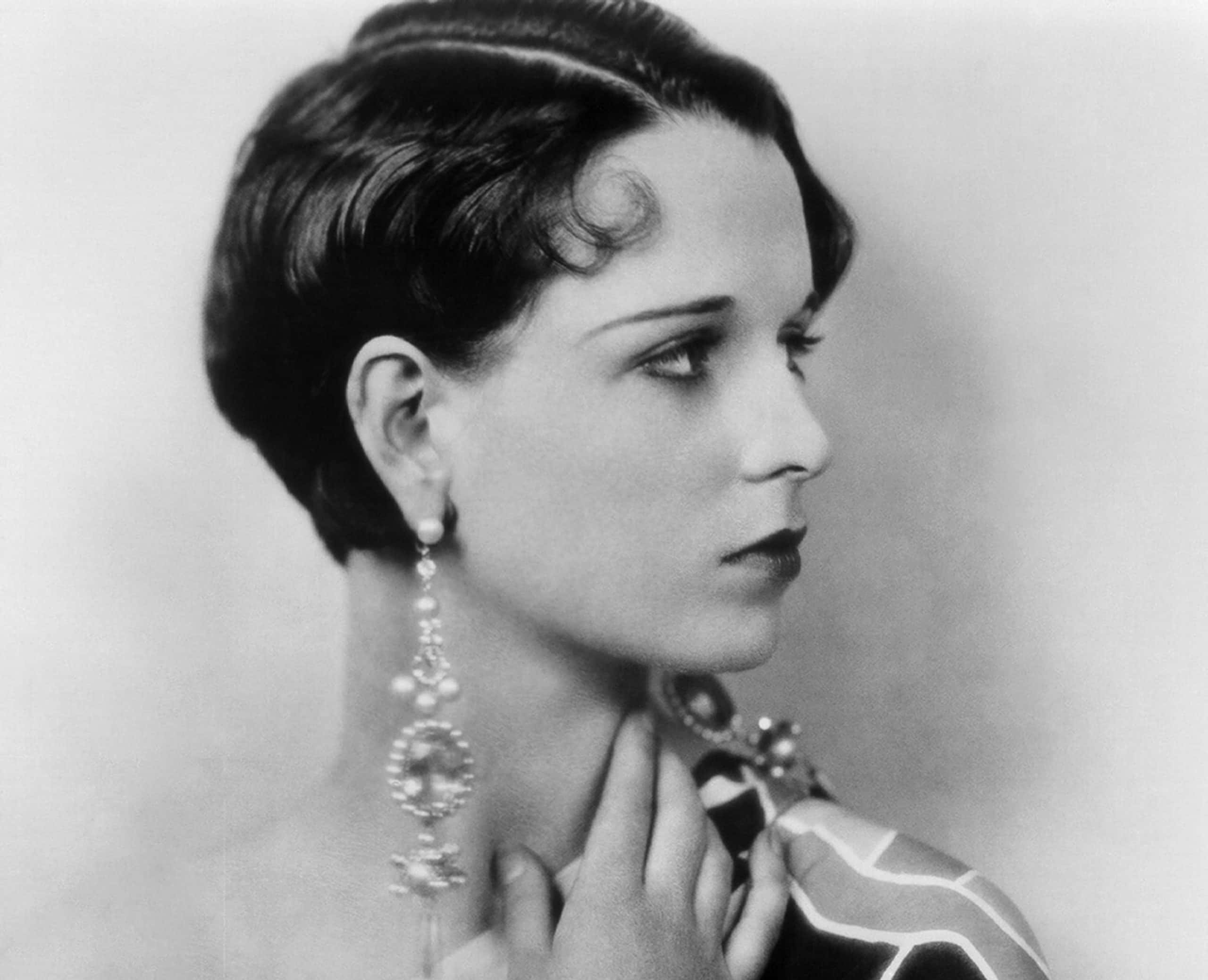 Actress Louise Brooks poses for a portrait session, wearing black and white dress, big earrings