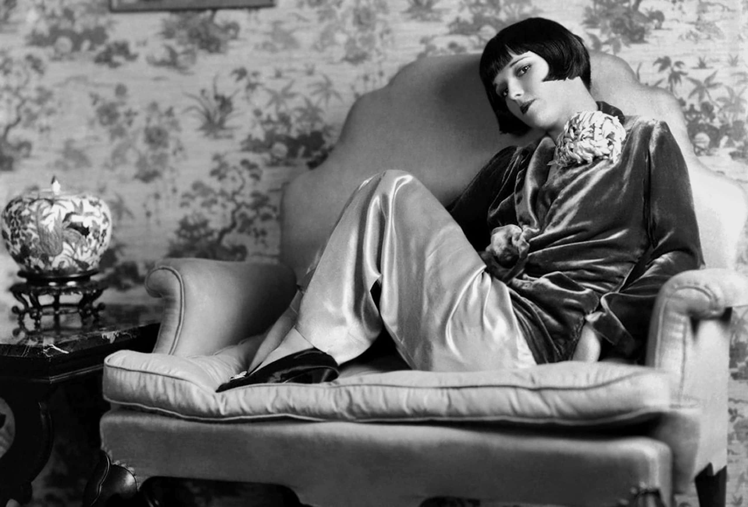 Actress Louise Brooks poses for a portrait session, sitting on a sofa