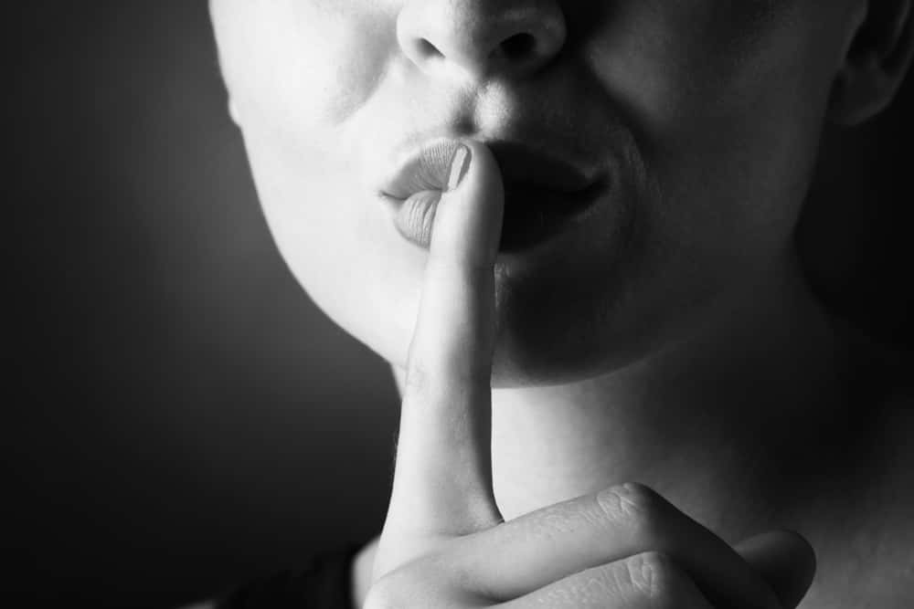 Молчание Shutterstock. Фото со знаком "молчание". Девушка вытирает губы молодому человеку. Картинка звук молчания. Обмен молчания