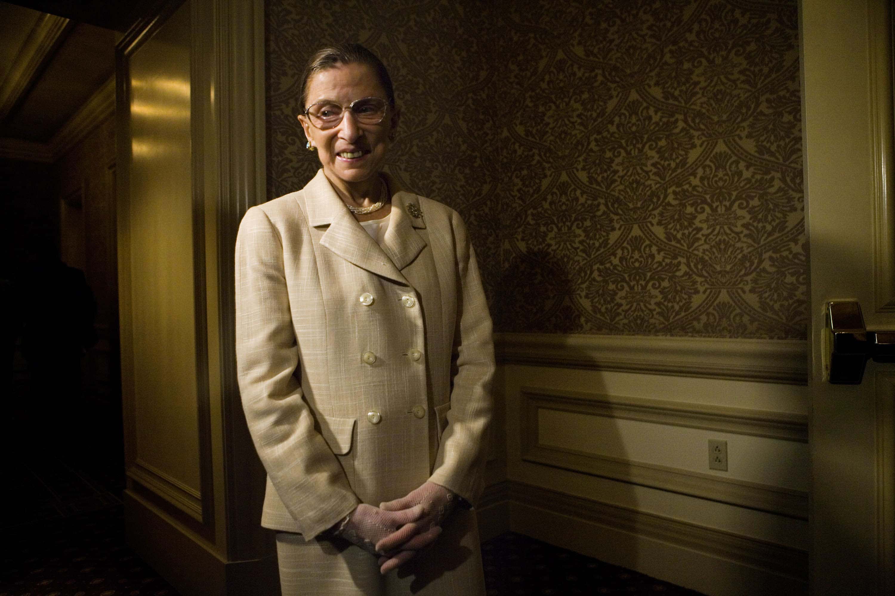 U.S. Supreme Court Justice Ruth Bader Ginsburg waits to enter a dinner to honor Michelle Bachelet, Chile's first female president in yellow  suit