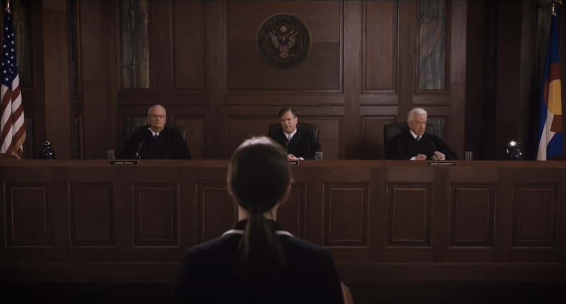 Felicity Jones as Ruth Bader Ginsburg in blue suit in front of judges