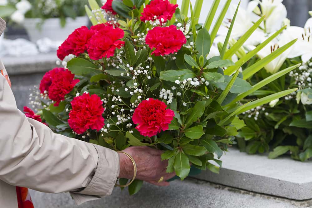 A woman leaving red flowers and candles in a graveyard