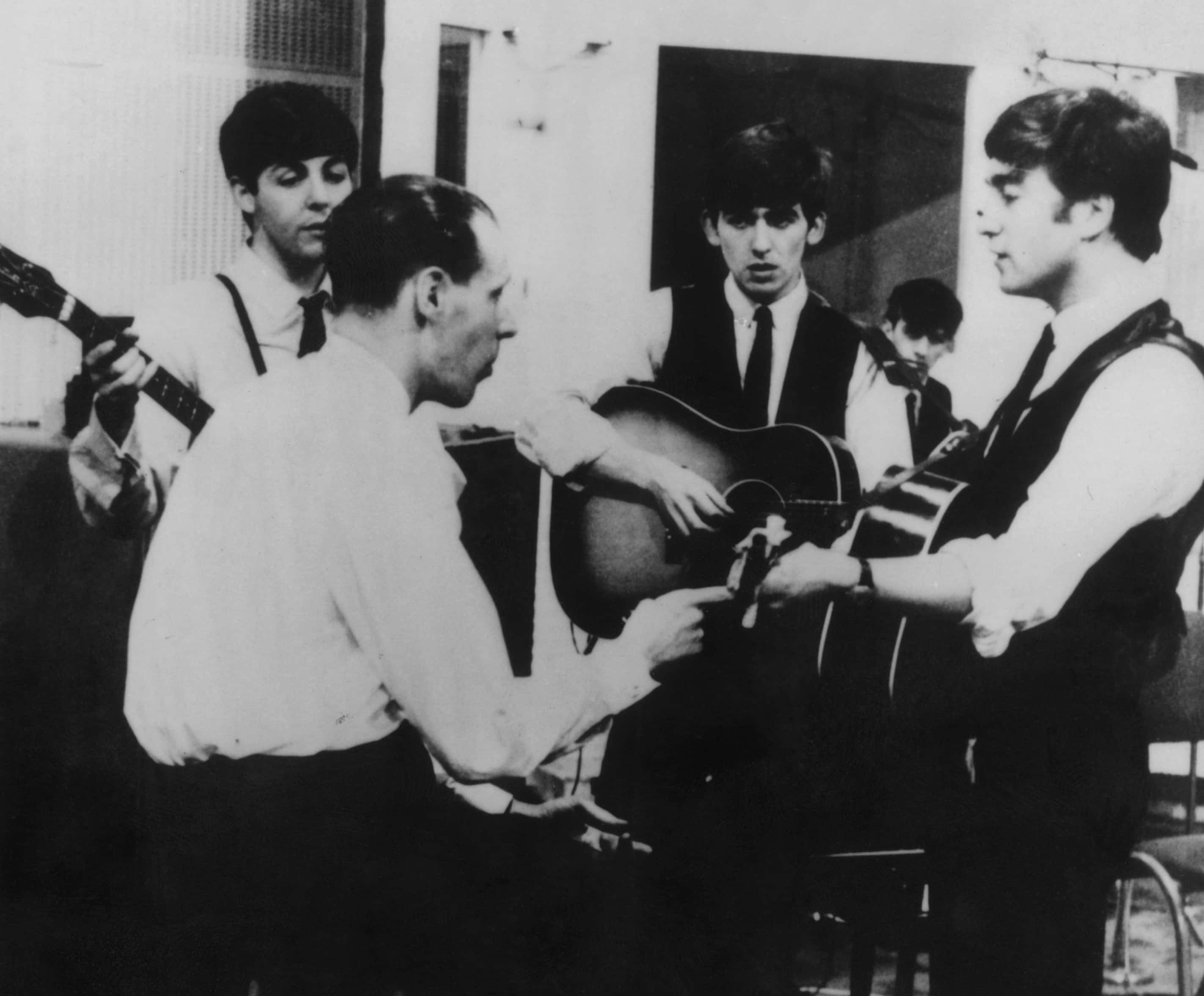 The Beatles at a recording session with their producer George Martin